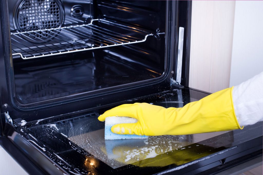 Professional cleaner scrubbing inside an oven during a move-out deep cleaning service