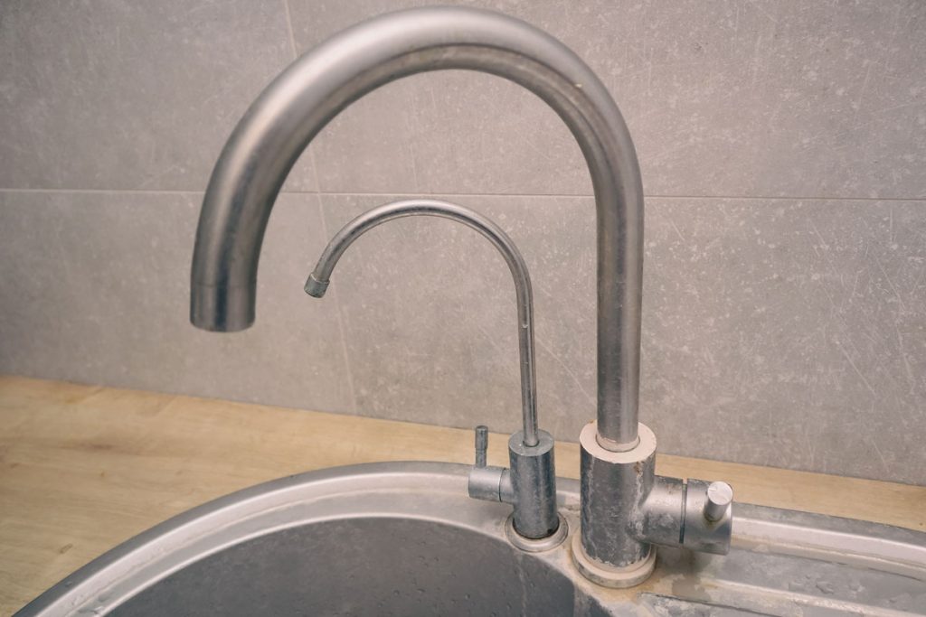 Kitchen faucet with hard water and mineral buildup before a professional deep cleaning service