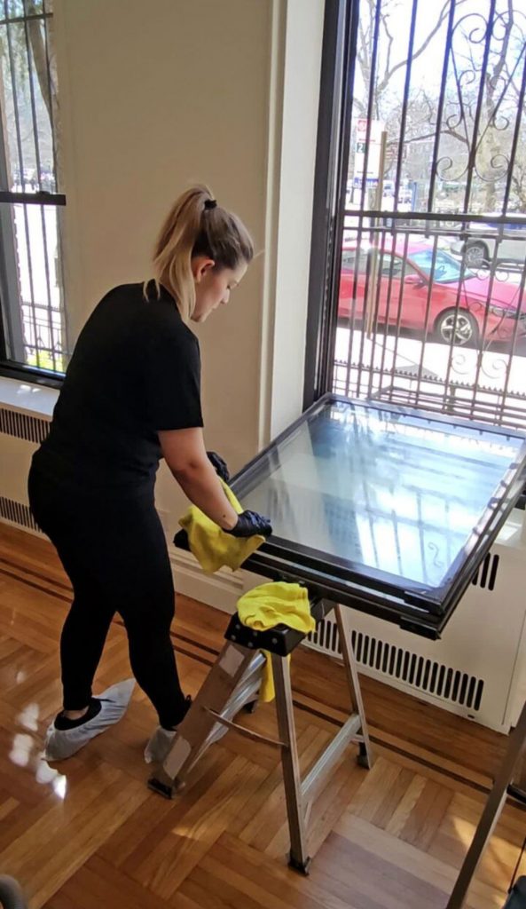 Professional cleaner wiping window glass during post-construction cleaning in residential home