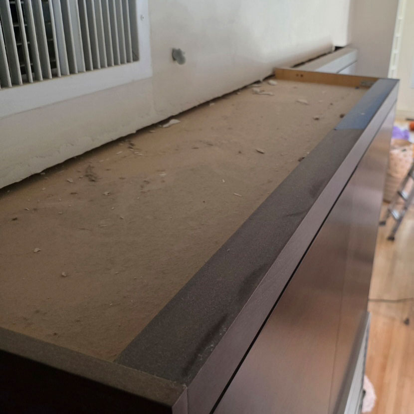 Dust and debris buildup above kitchen cabinetry after home repairs and renovation work