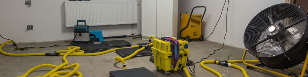Commercial air movers, dehumidifiers, and water extraction equipment drying a flooded basement during basement flood cleanup and water damage restoration