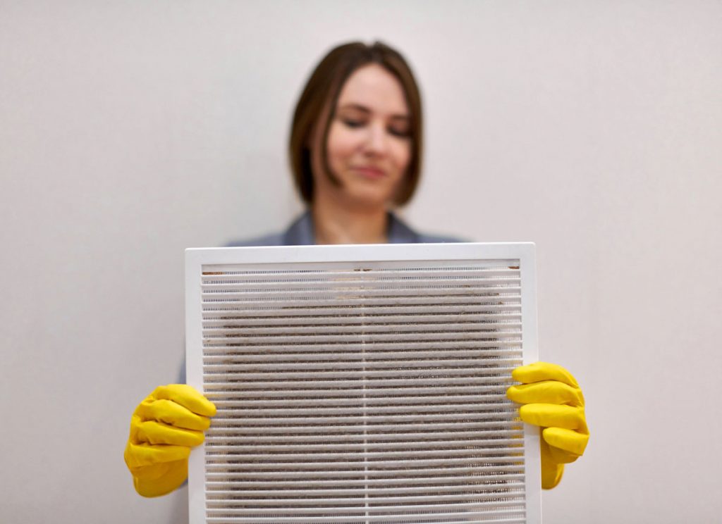 Dust-covered HVAC air filter after renovation showing construction dust buildup inside a home's ventilation system